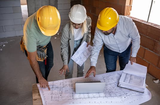 A female architect and a focused construction managers engage in an animated discussion, analyzing blueprints